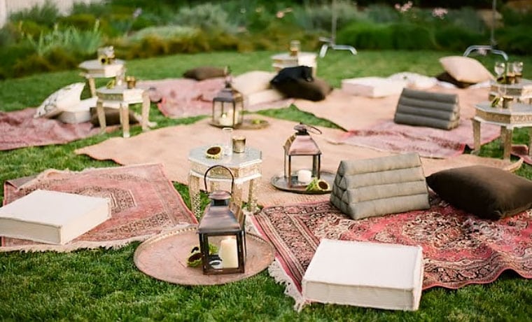 This setup uses a combination of cushions and throw rugs for seating, spiced up with rustic lanterns.